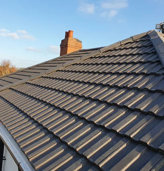 New grey tiled roof alongside the old worn roof it replaced